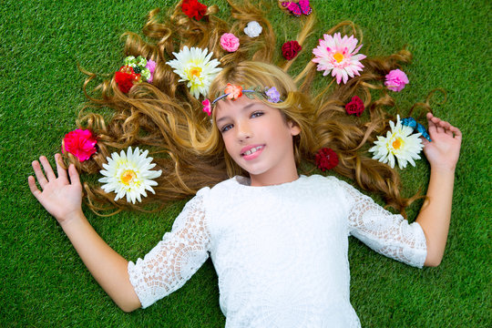 Blond spring girl with flowers on hair over grass