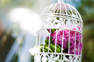 antique cage full of peonies hanging from a branch