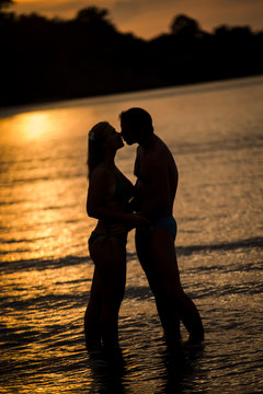 man and woman kiss on the beach having fun