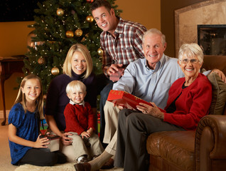 Multi Generation Family Opening Christmas Presents In Front Of T