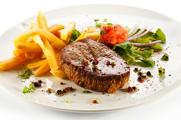 Grilled steaks, French fries and vegetables