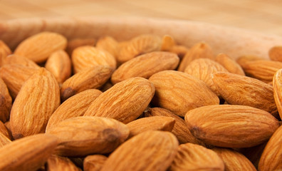 Raw almonds in wooden bowl close-up