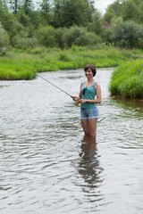 Девушка в майке и шортах ловит рыбу