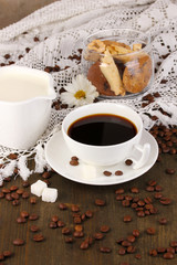 A cup of strong coffee and sweet cream on wooden table close-up