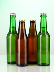 Coloured glass beer bottles on green background