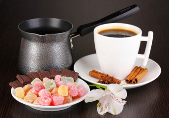 Cup of coffee with rahat delight and coffee pot on wooden table