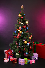 Decorated Christmas tree with gifts on dark color background