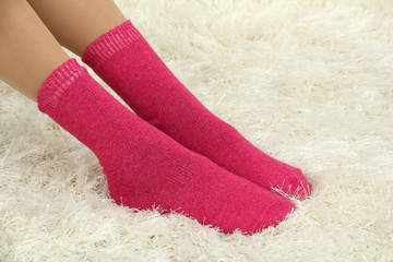 Female legs in colorful socks on  white carpet background