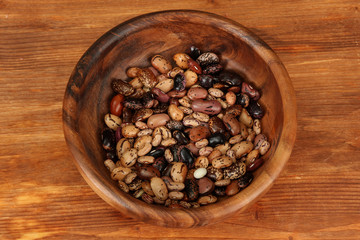Wooden bowl with beans on wooden background