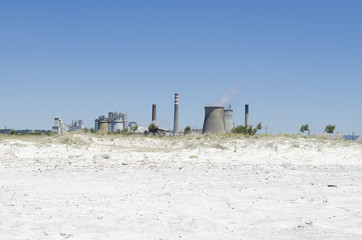 Chemical industry with cooling towers, beach and blue sky.