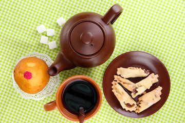 Top view of cup of tea and teapot on green tablecloths