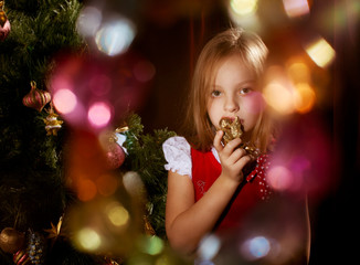 Little girl near Christmas tree with magic irradiance