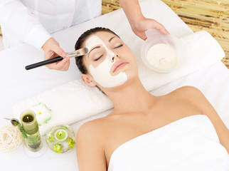 Young woman at spa salon with cosmetic mask on face