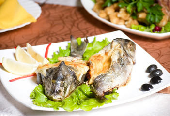 Fried fish garnished on sliced olive and sauce