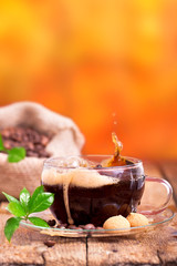 frischer Kaffe in Glastasse vor orangen Hintergrund