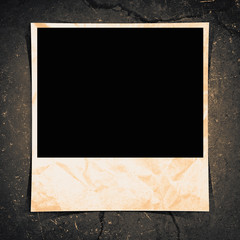 A blank instant photo taped to a grunge background.