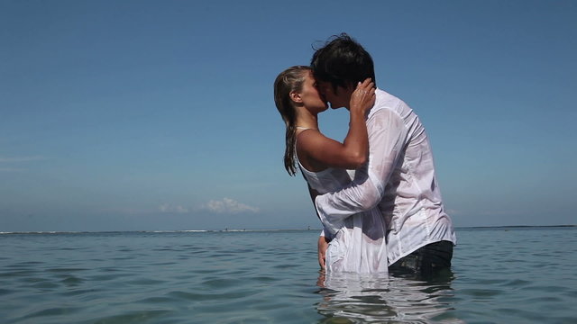 Passionate couple kissing and hugging each other in ocean