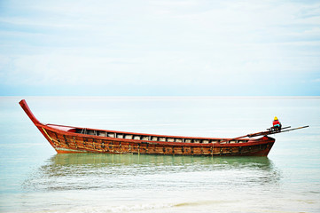 Asian style wooden long tail boat on the seashore