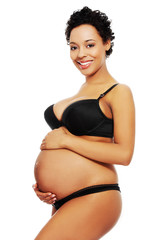 Pleased pregnant woman dressed in black lingerie.