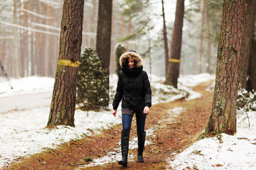 Woman is walking through forest in wintertime.