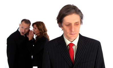 Mann mit flüsternden Kollegen im Hintergrund