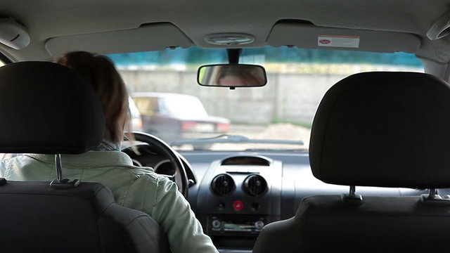 Woman inside of car looking in back mirror and trying to drive