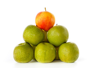 Stack of green apples and one yellow with red blush on top