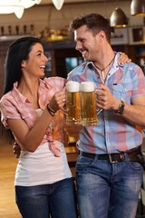 Happy young couple clinking with beer in pub