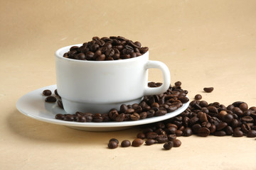 A cup full of coffee beans, isolated on yellow, closeup