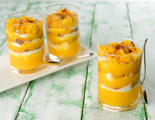 Dessert with mango in a glass on a white table