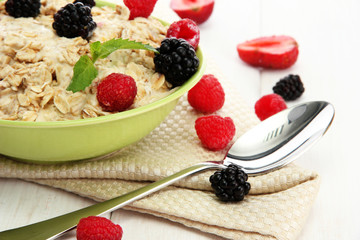 tasty oatmeal with berries, on white wooden table