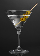 Martini glass and olives on grey background