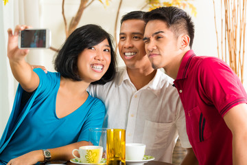 Asian friends taking pictures with mobile phone