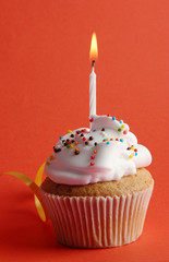 tasty birthday cupcake with candle, on red background