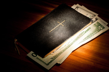 Bibel mit Geldscheinen im Spotlight