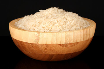 White polished rice in wooden bowl isolated on black
