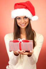 beautiful young woman with gift, on red background