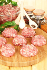 Raw meatballs with spices on wooden table