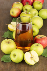 Useful apple juice with apples around on wooden table