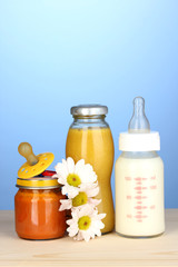 Baby food, bottle of milk, puree and juice on blue background