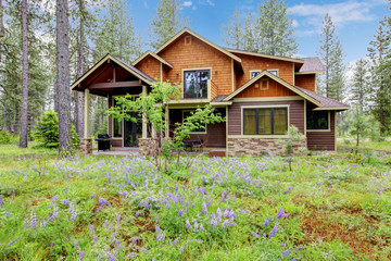 Mountain cabin home exterior with forest and flowers.
