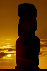 Silhouette of a moai against orange sunrise