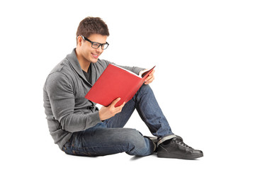 Smiling guy sitting on a floor and reading a book