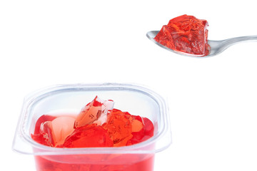 Spoon full of red gelatin. Against the background of the package