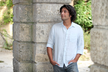 Man leaning by old stone wall