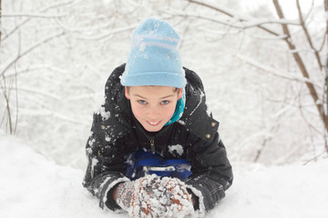 Fototapeta na wymiar kłamstwo chłopiec na śniegu i śnieżki rze¼bić w zimowym lesie