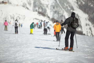 Group of skiers on snowy hillslope, focus on nearest skier