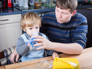 Little boy and his father making inhalation with nebuliser