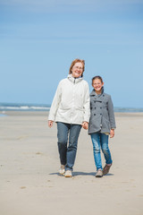 Girl and her grandmother walking on the beach