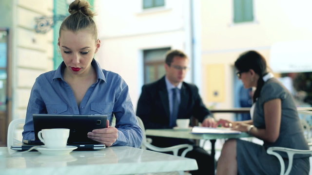 Businesswoman with tablet computer working in cafe, outdoors